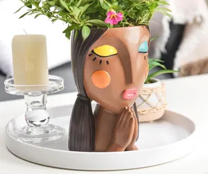 Macro view of face planter pot featuring closed eyes and hand-painted makeup details