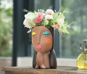 Detailed resin girl planter in prayer pose with vibrant makeup and artificial flowers