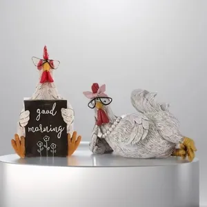 Close-up of resin rooster and hen statues with good morning sign and cute accessories