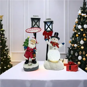 Close-up of lighted Santa Claus and Snowman resin ornaments with glowing welcome street lamps