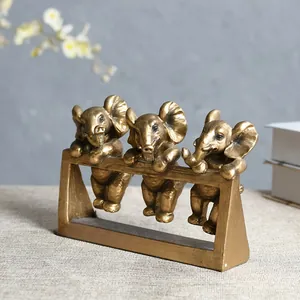 Drie gouden olifantjes van hars klimmend op een frame voor stijlvolle tafeldecoratie