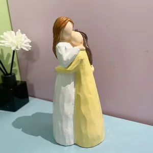 Vue détaillée d'une figurine en résine sans visage montrant deux femmes s'enlaçant