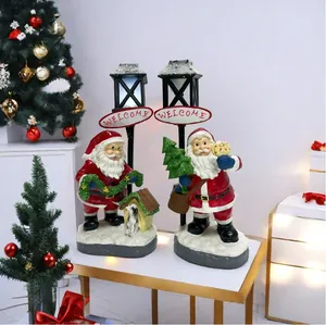 Detail of lit Santa Claus resin figurines with retro street lamps and welcome sign