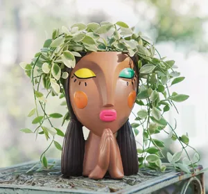 Close-up of creative resin girl planter with prayer pose and artistic face painting