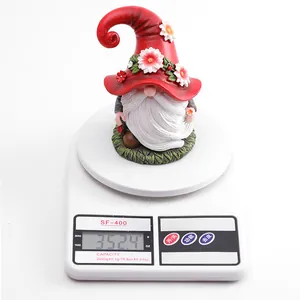 Resin Christmas gnome ornament with red floral hat weighing 352.4g on a scale