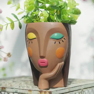 Artistic face resin flower pot with faux greenery on a vintage stand for garden decor