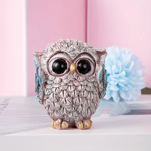 Detailed macro view showing the textured resin feathers and gold accents on owl figurines
