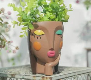 Detail view of artistic resin girl face planter with colorful makeup on a metal base