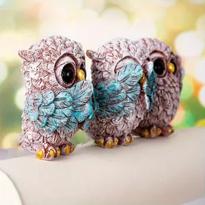 Macro detail of three owl resin figurines with blue wings and gold accents