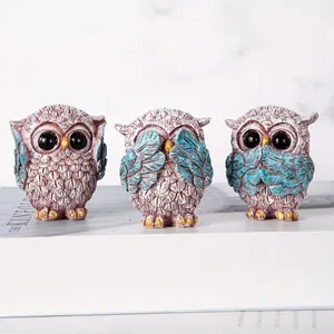 Macro detail of three pink and blue owl resin statues with intricate feather textures