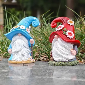 Detail view of resin Christmas gnomes with long white beards and daisy hats in a garden