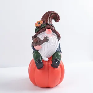 Solar powered garden gnome statue with sunflower hat sitting on a pumpkin with a snail