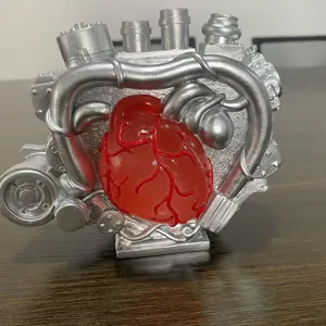 Mechanical heart engine ornament in silver and red on a rustic wooden desk surface