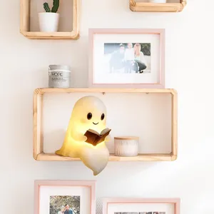 Détail d'une adorable lampe fantôme lisant un livre avec lumière chaude et décor bois