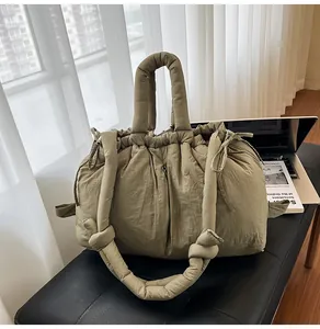 Detailed shot of khaki quilted puffer tote bag on a black bench with lifestyle accessories