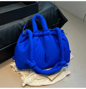 Detail of blue quilted puffer tote with padded handles and knotted shoulder strap