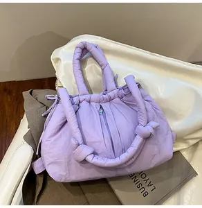 Detail of light purple quilted puffer tote bag with knotted handle on a leather chair