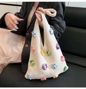 Détail d'un sac cabas en tricot crème avec des fleurs 3D au crochet de couleurs vives