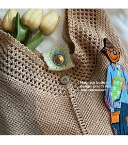 Detail of magnetic buckle closure on beige knitted tote bag with cartoon embroidery