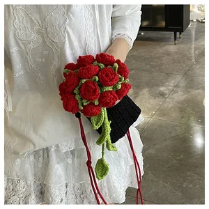Détail du sac crocheté main avec roses rouges 3D et feuilles vertes sur tricot noir
