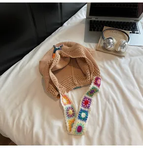 Detail of hand-crocheted sunflower strap on a beige knit tote bag with metal button closure