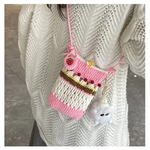 Detail of handmade crochet crossbody bag with strawberry and plush doll pendant charms