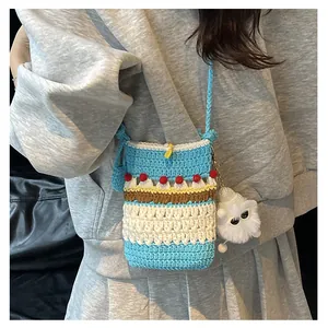 Close-up of handmade crochet crossbody bag with blue cream cake design and pom-poms