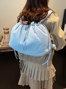 Light blue padded drawstring backpack with quilted texture shown on a model