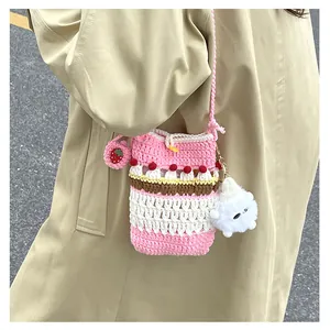 Detail of handmade crochet crossbody bag with cupcake design and strawberry charm