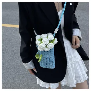 Detail der blauen Häkeltasche mit weißen Rosen und grünen Blättern am Schultergurt