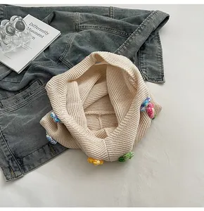 Detailansicht der cremefarbenen Stricktasche mit bunten 3D-Häkelblumen auf Denim