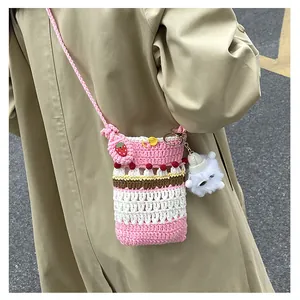 Detail of handmade crochet crossbody bag with strawberry decor and plush charm