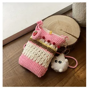 Detailed view of hand-crocheted cake-style phone bag with strawberry button and plush charm