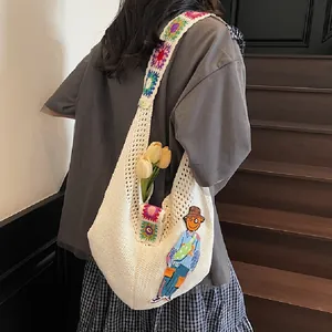 Detailed shot of crochet shoulder bag featuring colorful floral strap and character embroidery