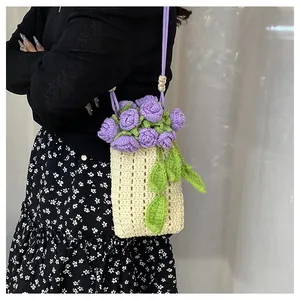 Detailed close-up of a hand-knitted floral mini bag with 3D purple roses and green leaves