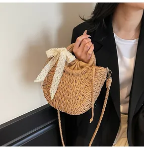 Détail du sac seau en paille avec nœud en dentelle blanche et doublure à cordon