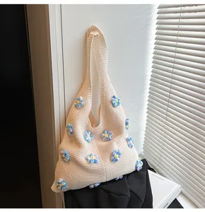 Detail einer cremefarbenen Stricktasche mit handgefertigten 3D-Blumenapplikationen