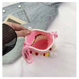Detailed top view of handmade crochet pink crossbody bag with colorful charms and inner space