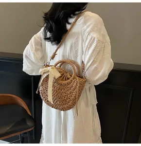 Détail d'un sac en paille tressée avec nœud en dentelle et chaîne de perles élégante