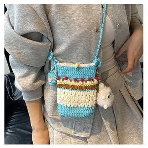Detail of handmade crochet phone bag with cake design and cute strawberry charm