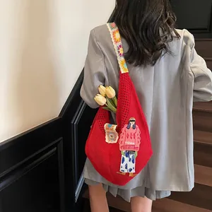 Macro view of red oversized crochet bag with cartoon embroidery and floral strap details