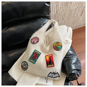 Gros plan d'un sac cabas en tricot crème avec broderies colorées et écussons Sasquatch