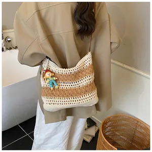 Detail of hand-woven cotton striped bag with cute boy doll charm and brown strap