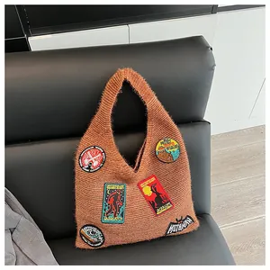 Détail du sac en tricot marron avec badges brodés de créatures mystiques