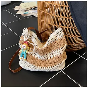 Detail of hand-woven cotton beach bag with leather strap and cute doll pendant accessory