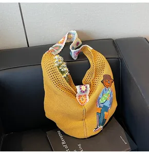 Detail of yellow crochet knit tote bag with floral strap and boy embroidery motif