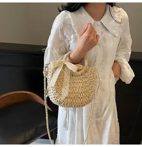 Détail du sac en paille tressé avec nœud en dentelle et fermeture à cordon