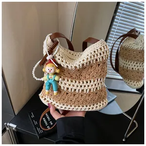 Close-up of woven cotton tote bag with hollow patterns and cute doll pendant