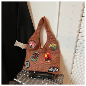 Détail du sac en tricot marron avec écussons brodés Sasquatch et Mothman