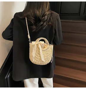 Détails du sac seau en paille avec nœud en dentelle et bandoulière tissée